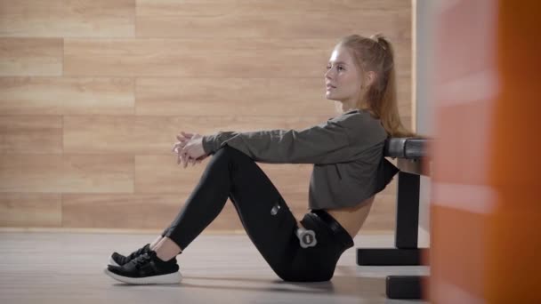 Une belle fille mince dans une salle de gym. Une jeune femme se détend pendant une séance d'entraînement . — Video