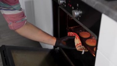Kocası fırında pişirilmiş kurabiyeleri çıkarıyor. Pişirme aile gelenekleri.