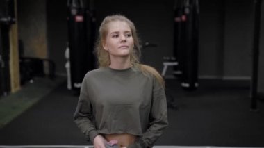 Genç ve güzel bir kadın, antrenörlüğünü spor salonunda bitirdi. Sarışın kız gider ve su içer..