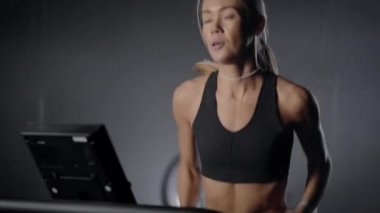 Slender blonde on a treadmill in the gym. A girl with a beautiful figure and a tight-up pres. Running in the gym.