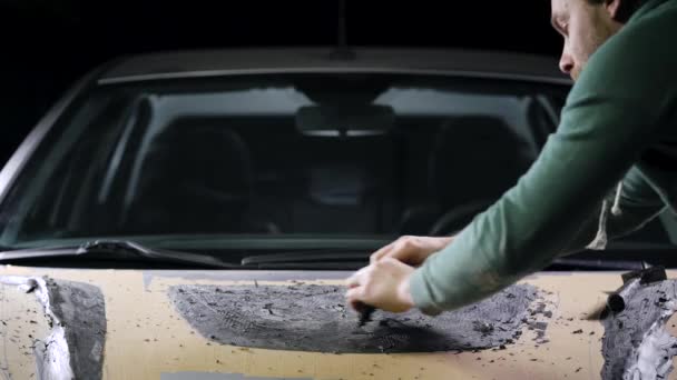 Un maestro con dei passanti nelle mani mostra la forma di una parte. Un uomo lavora su un modello di cappuccio sportivo per un'auto. Tuning atelier — Video Stock