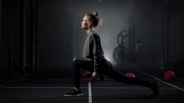 Jeune femme sexuelle fait des fentes avec haltères dans les mains dans la salle de gym moderne, jambes d'entraînement — Video