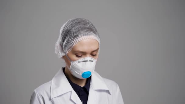 Женщина с медицинской маской на лице ждет пациентов с гриппом и вирусом в клинике, средний портрет — стоковое видео