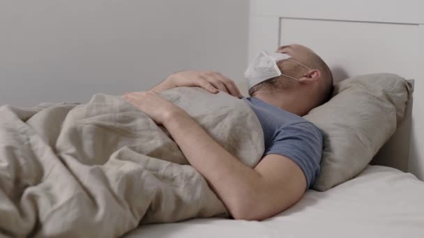 Чоловік страждає гарячкою, високою температурою і кашлем, лежачи в ліжку під час сезонної епідемії грипу та респіраторних інфекцій — стокове відео