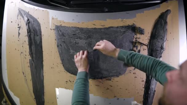 A master with loops in his hands displays the shape of a part. A man works on a mock-up of a sports hood for a car. Tuning atelier — Stock Video