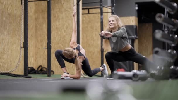 Młode kobiety trenują razem w centrum fitness na siłowni, rozciągając mięśnie nóg, grupowy trening — Wideo stockowe