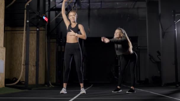 Pair of attractive athletic women workout in gymnastic hall at evening, stretching and warming muscles — Stok video