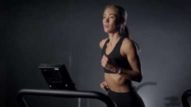 sexy young woman is jogging on moving walk in fitness club, training her endurance, cardio workout
