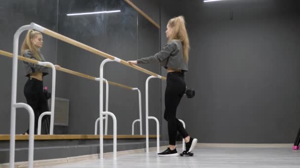 Femme sexuelle s'entraîne seule dans la salle de fitness, tenant haltère dans la main et accroupi devant le miroir — Video