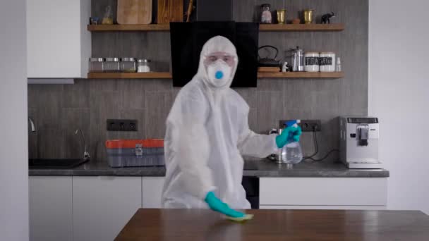 Pandemic Covid-19. A man in a protective suit, dancing and rejoicing. The room is treated with antiseptic and prosifine — Stock Video