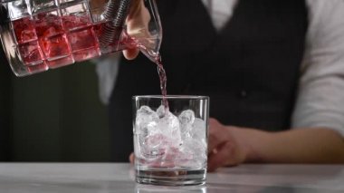 Gece barında yakın çekim. Barmen bitmiş kokteyli bardağa doldurur. Endüstride güzel bir içecek kaynağı önemlidir..