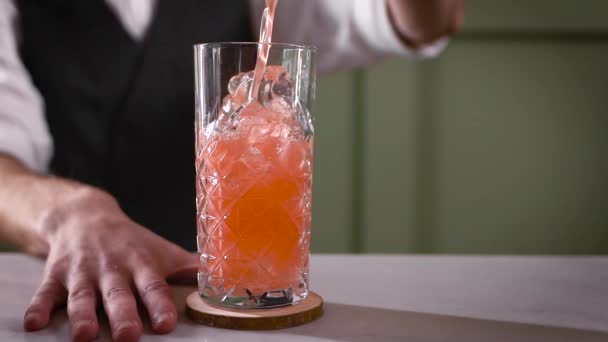 Zbliżenie w nocnym barze. Barman wlewa gotowy koktajl do szklanki. Piękne dostawy napojów są ważne w branży. — Wideo stockowe