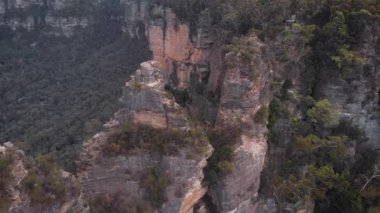 Blue Mountains Ulusal Parkı. Üç kız kardeş, yeşil bir çalılığın ortasındaki güzel uçurumlar. Hava görünümü