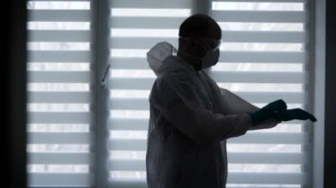 Salgın Covid-19. Silüet epidemiyoloji uzmanı koruyucu kıyafet giyiyor.