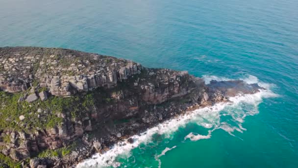 Um belo promontório rochoso repousa contra o oceano — Vídeo de Stock