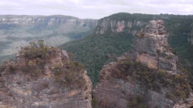 Blue Mountains Ulusal Parkı. Üç kız kardeş, yeşil bir çalılığın ortasındaki güzel uçurumlar. Hava görünümü