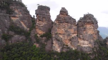 Blue Mountains Ulusal Parkı. Üç kız kardeş, yeşil bir çalılığın ortasındaki güzel uçurumlar. Hava görünümü