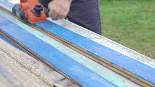 Der Schreiner arbeitet als Elektrobank. Die Bearbeitung einer alten Holzplatte. Restaurierungsarbeiten. — Stockvideo