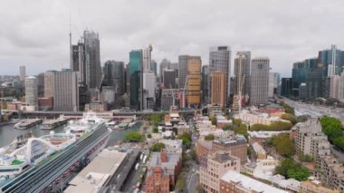 Sydney şehir merkezinden yukarıdan bak. Çerçevede gökdelenler, liman, yolcu gemisi ve körfez.