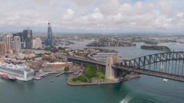 Hava görüntüsü. Central Sydney ve Rocks bölgesi. Çerçevede bir köprü, gökdelenler, körfez ve liman var..