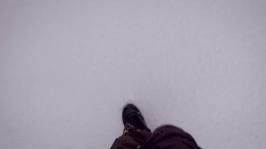 Snowboard yapan kış botlu bir adam karda yürüyor..