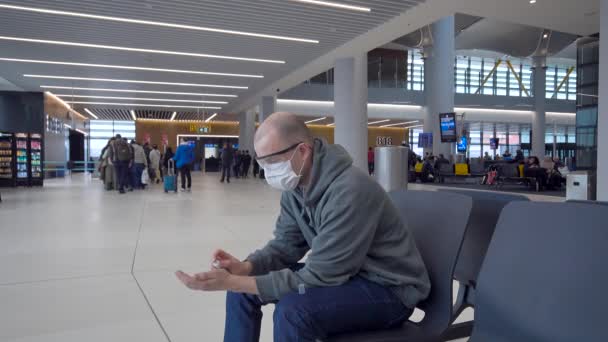 Um homem na sala de espera do aeroporto internacional. As proteções devem ser usadas durante uma epidemia . — Vídeo de Stock
