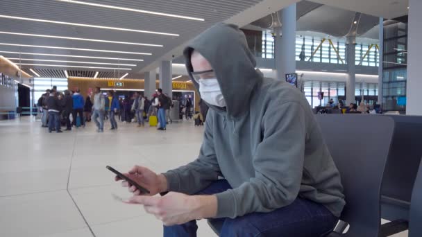 Um homem na sala de espera do aeroporto internacional. As proteções devem ser usadas durante uma epidemia . — Vídeo de Stock