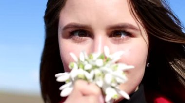 Güzel gülümseyen esmer kız elinde bir buket kardamlası tutuyor ilk bahar çiçekleri.