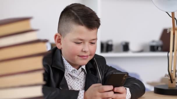 Мальчик не хочет читать книги, но использует смартфон для развлечения — стоковое видео