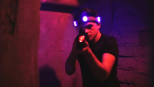 Modern young people playing laser tag on dark labyrinth in bright beams — Stock Video