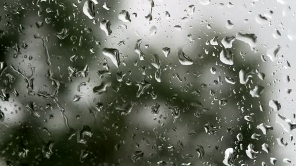 창문 유리 표면에는 구름낀 배경으로 비가 내린다. 구름낀 배경에 고립 된 자연적 인 빗방울 무늬. — 비디오