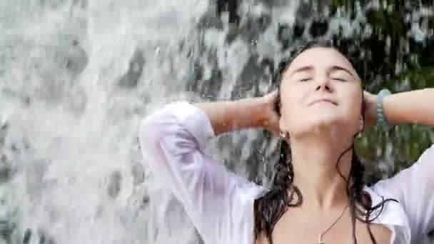 Ung vacker och söt asiatisk kvinna i bikini få kropp våt under ström av naturliga fantastiska vattenfall sitter på rock känsla renhet och frihet i hemlig natur skönhet resmål — Stockvideo