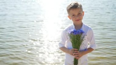 Sevimli ve güzel bir çocuk, elinde bir buket çiçekle bir çocuk. 8 Mart, Uluslararası Kadınlar Günü, Anneler, Anneler ve Oğullar Günü. Çiçek hediyesi.