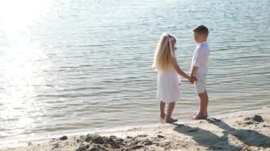 Güneşli bir günde gölette kardeş, mutlu çocuklar, çocuklar için yaz tatili, çocuklar nehir kenarında eğleniyor.