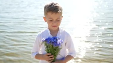 Sevimli ve güzel bir çocuk, elinde bir buket çiçekle bir çocuk. 8 Mart, Uluslararası Kadınlar Günü, Anneler, Anneler ve Oğullar Günü. Çiçek hediyesi.