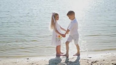 Erkek ve kız kardeş sahilde eğleniyor. Oyuncak bir tekne ve gemiden bir oğlan ve bir kız, çocuklar kağıt bir gemiyle oynuyorlar.