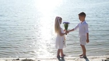 Oğlan ve kız bir yaz günü gölde yürürler, mutlu çocuklar güneşli bir günde göletin yanında yürürler.