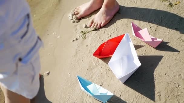 兄と妹はビーチで楽しんでいます おもちゃのボートと船の男の子と女の子 子供たちは紙の船で遊ぶ — ストック動画