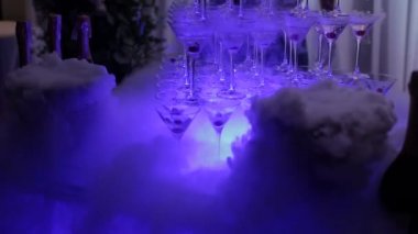 Şampanya kaydırağı. Kirazlı şampanya bardaklarından yapılmış piramit ya da çeşme ve kuru buz ağır çekimde buhar.