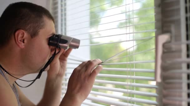 The man is spying on people, using binoculars — Stock Video