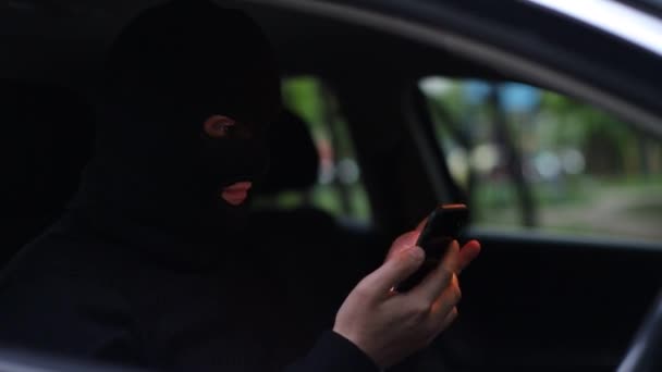 El criminal enmascarado está hablando en un teléfono inteligente, intimidando a la víctima — Vídeo de stock