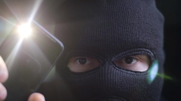 Нападающий с фонариком в темной маске обыскивает комнату — стоковое видео