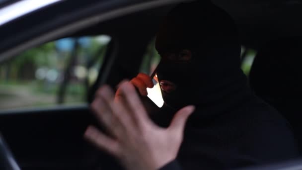 Террорист в черной маске в машине — стоковое видео
