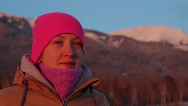 Portret van een lachende jonge vrouw aan de voet van de bergen bij zonsondergang — Stockvideo