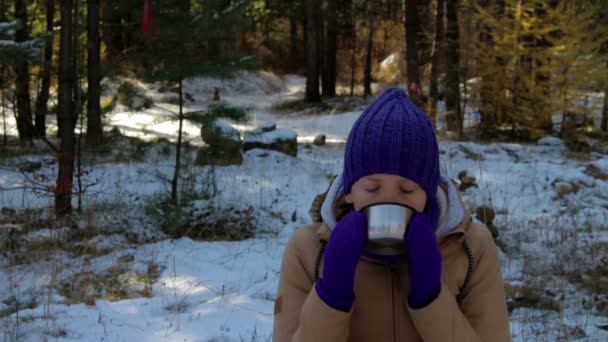 Ung kvinna dricker varmt te eller kaffe i vinter skog — Stockvideo