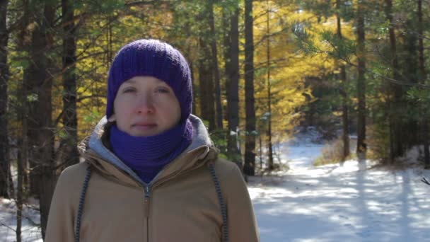 Retrato de una mujer joven en un bosque invernal nevado en un día soleado . — Vídeo de stock