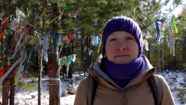 Portrét mladé ženy v zimním lese poblíž strom s barevnými stužkami — Stock video