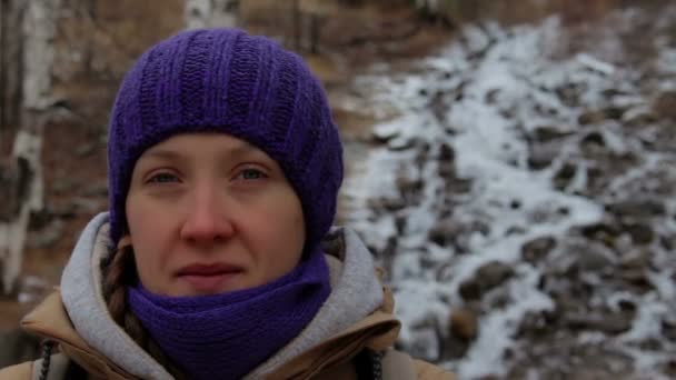 Retrato de una niña cerca de un arroyo de montaña en el bosque de invierno. Primer plano — Vídeo de stock