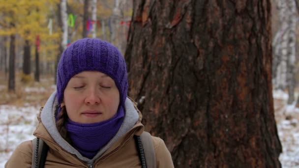 Mujer joven meditando cerca del viejo árbol grande en el bosque de invierno. Primer plano — Vídeo de stock