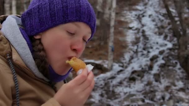 Flicka äter tårta och dryck te på en ström i vinter skogen — Stockvideo